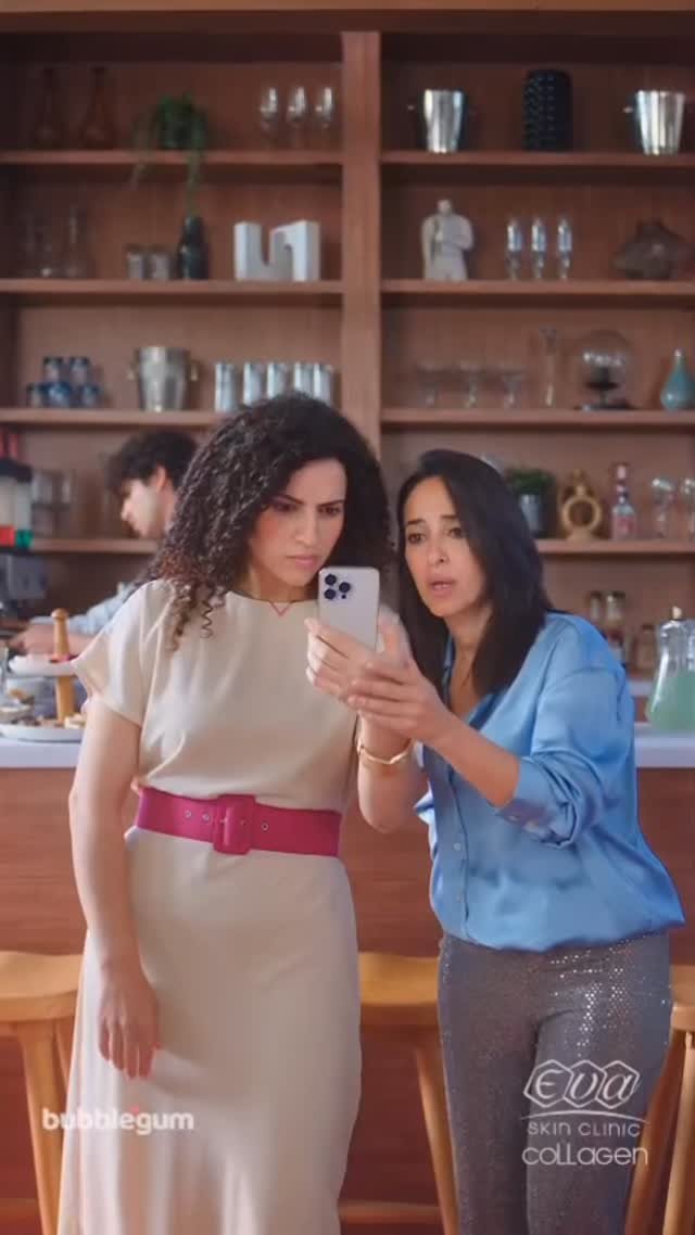 Two women looking at a mobile phone in a café, with the Eva Skin Clinic Collagen logo in the corner.